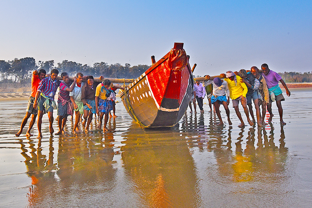 a group of people walking on a beach with a boat